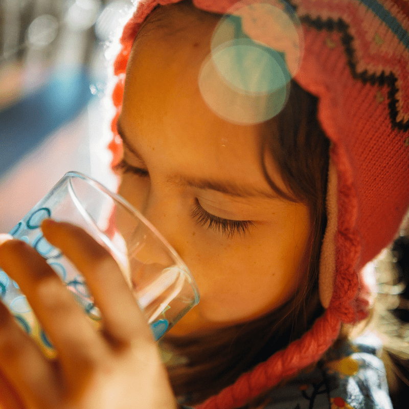 A child drinking from a glass of water.