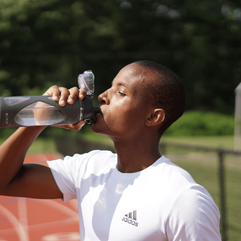 A man drinking water from a tumbler.