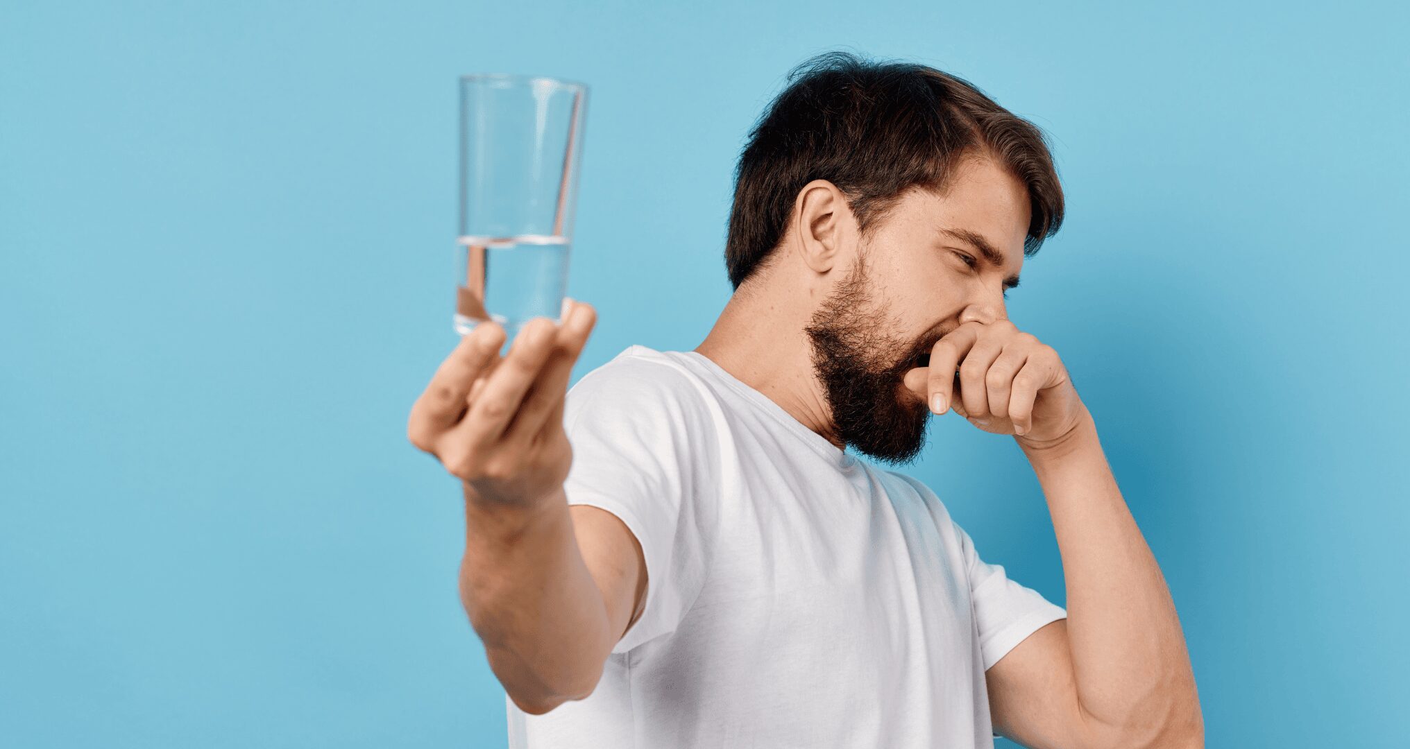 man holding stinky glass of water out away from himself