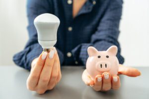 female hand holding light bulb and piggy bank