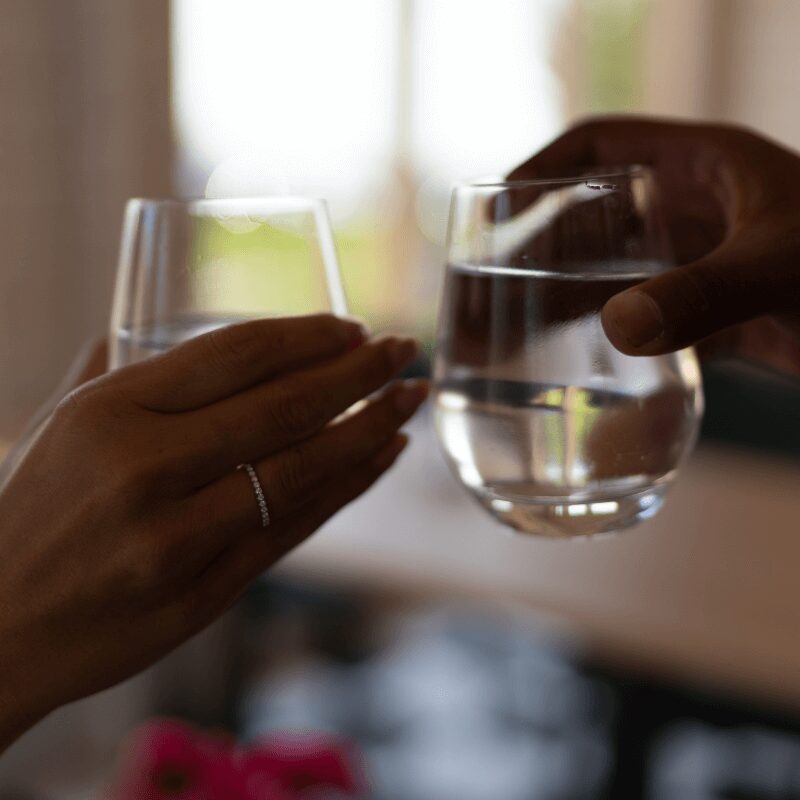 two individuals holding glasses of water close up